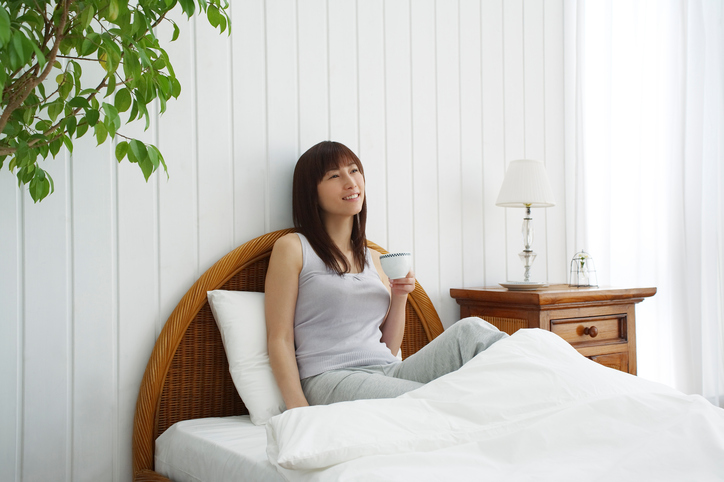 Young Woman in Bed Drinking Tea, Front View